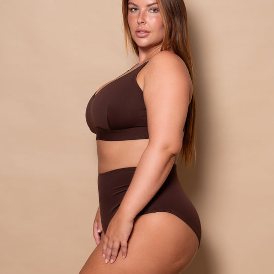 plussize woman wearing a chocolate brown bikini set against a beige background