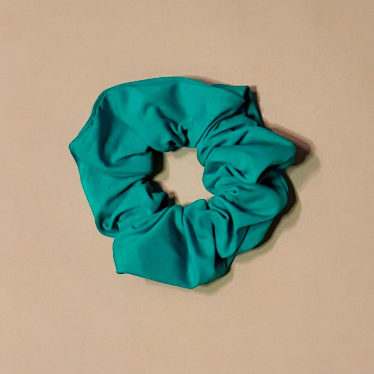 emerald green scrunchie on a beige background