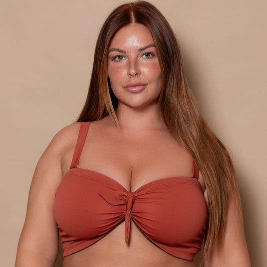 plussize woman wearing a rust red bikini set against a beige background
