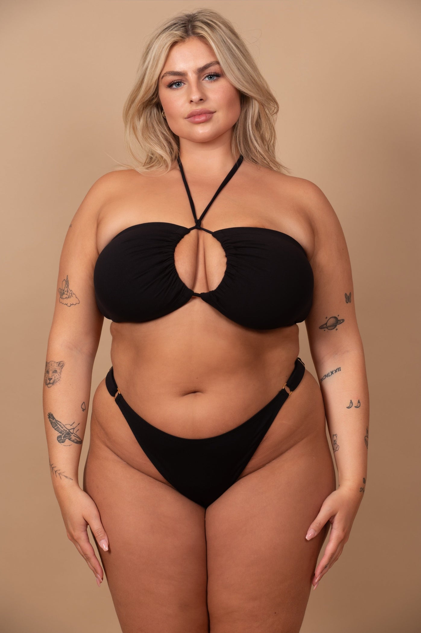 curvy woman wearing a black bikini against a beige background