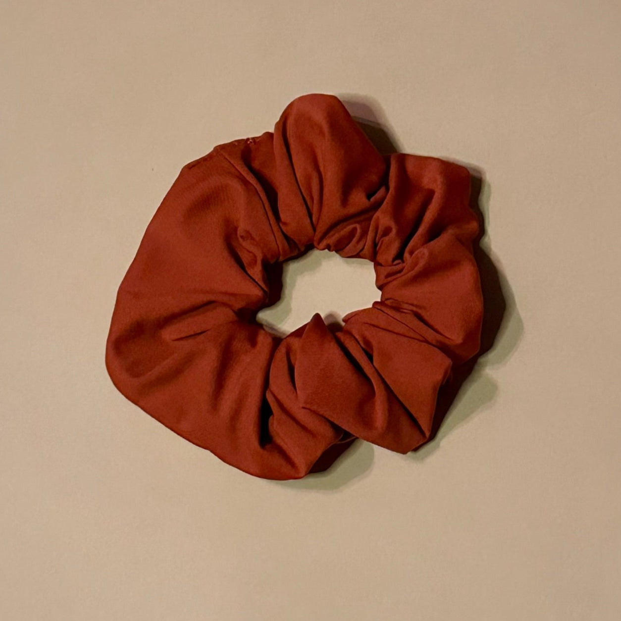 rust red scrunchie on a beige background
