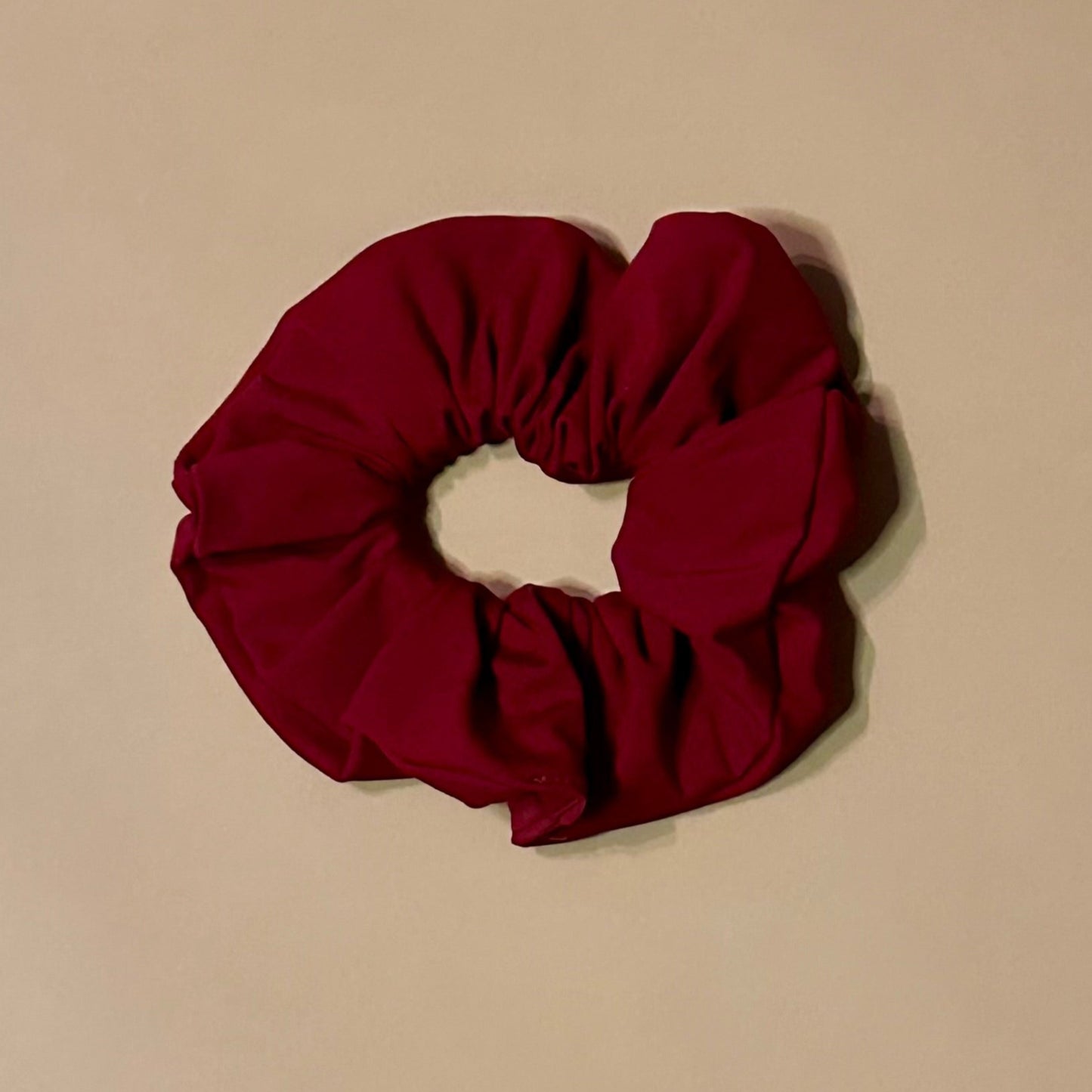 wine red pomegranate scrunchie on a beige background