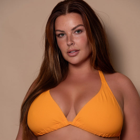 curvy woman wearing a yellow ribbed bikini triangle against a beige background