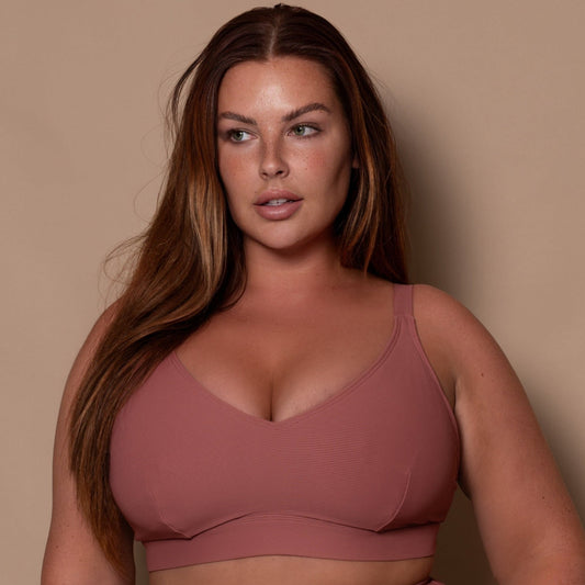 plussize woman wearing a rosewood pink bikini against a beige background