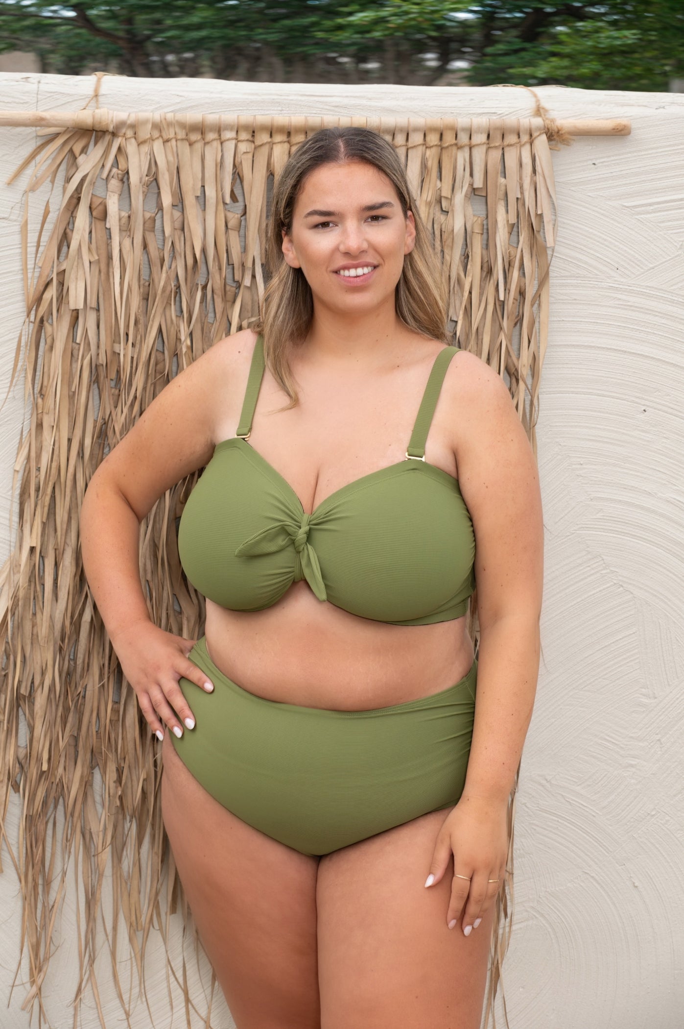 plussize woman wearing a green khaki bikini set against a beige background