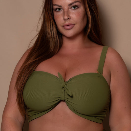 plussize woman wearing a khaki green bandeau bikini against a beige background