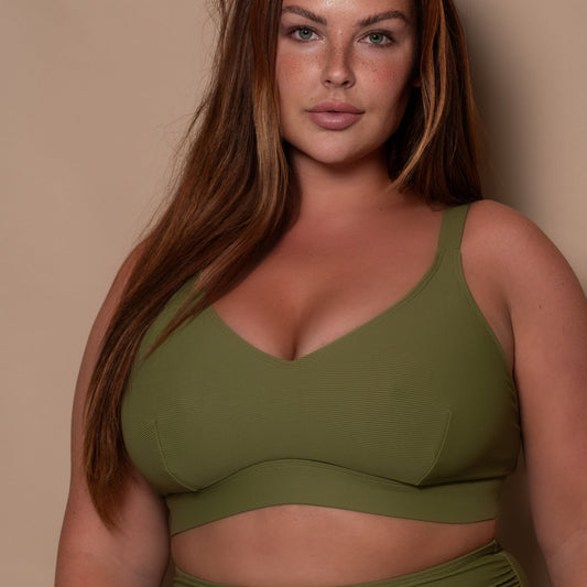 plussize woman wearing a khaki green bikini against a beige background