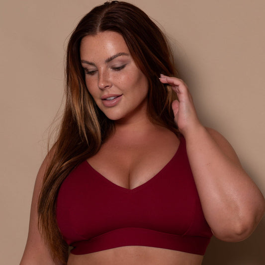 plussize woman wearing a pomegranate red bikini against a beige background