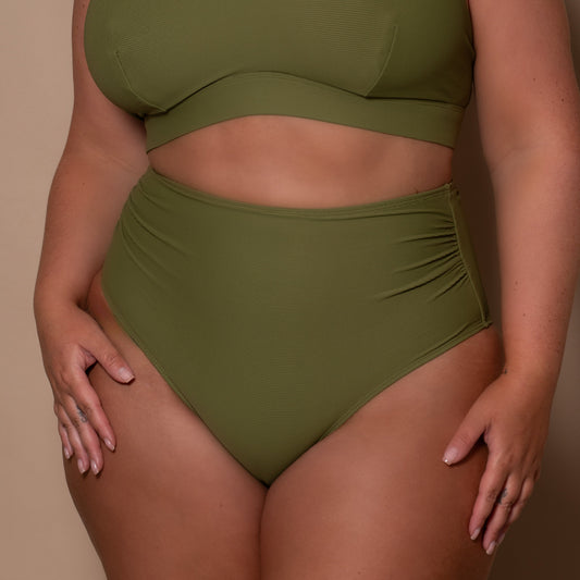 plussize woman wearing a khaki green bikini against a beige background