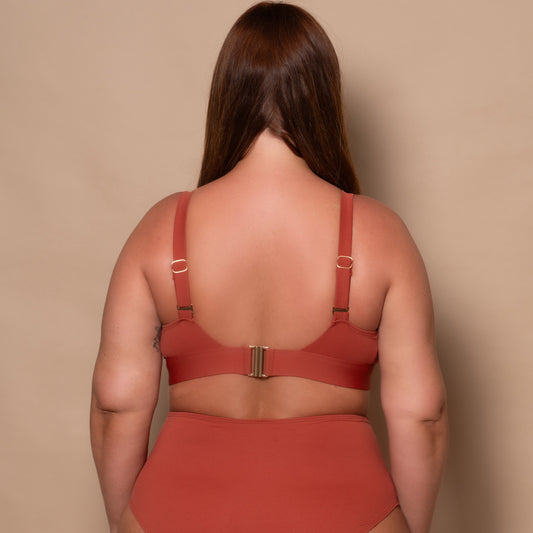 plussize woman wearing a rust red bikini set against a beige background