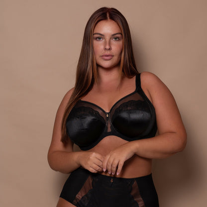 plussize woman wearing a black lingerie set against a beige background