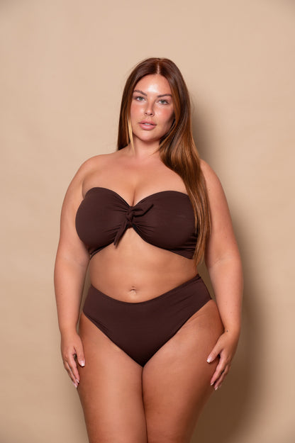 curvy woman wearing a chocolate brown bikini set against a beige background