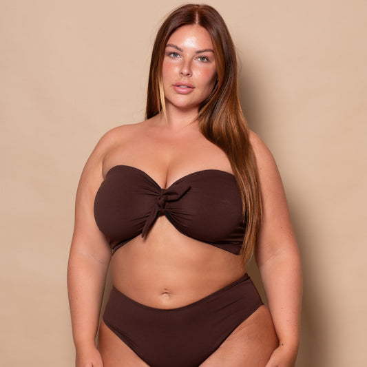 plussize woman wearing a chocolate brown bikini set against a beige background