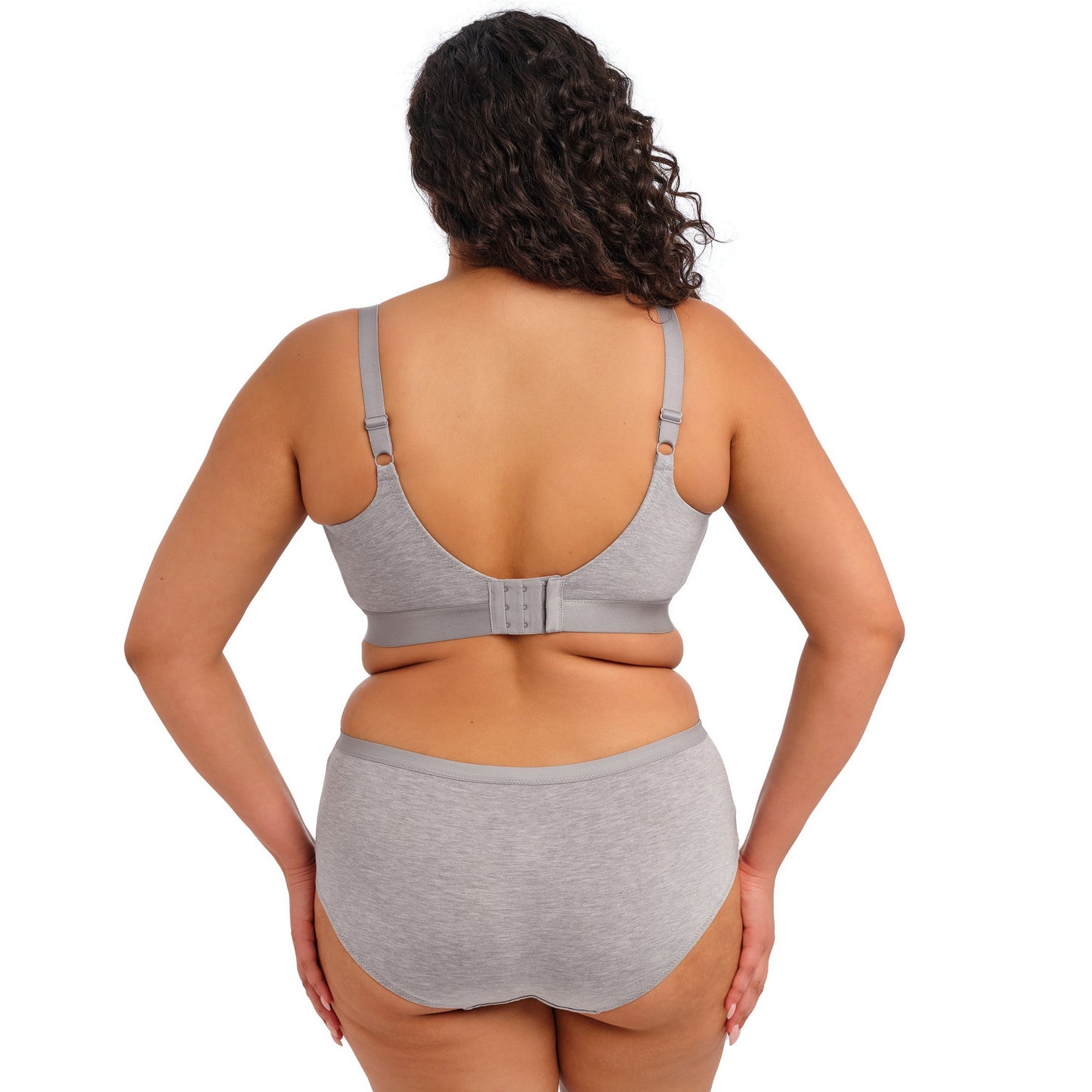Curvy woman wearing a grey bra and underwear set against a white background