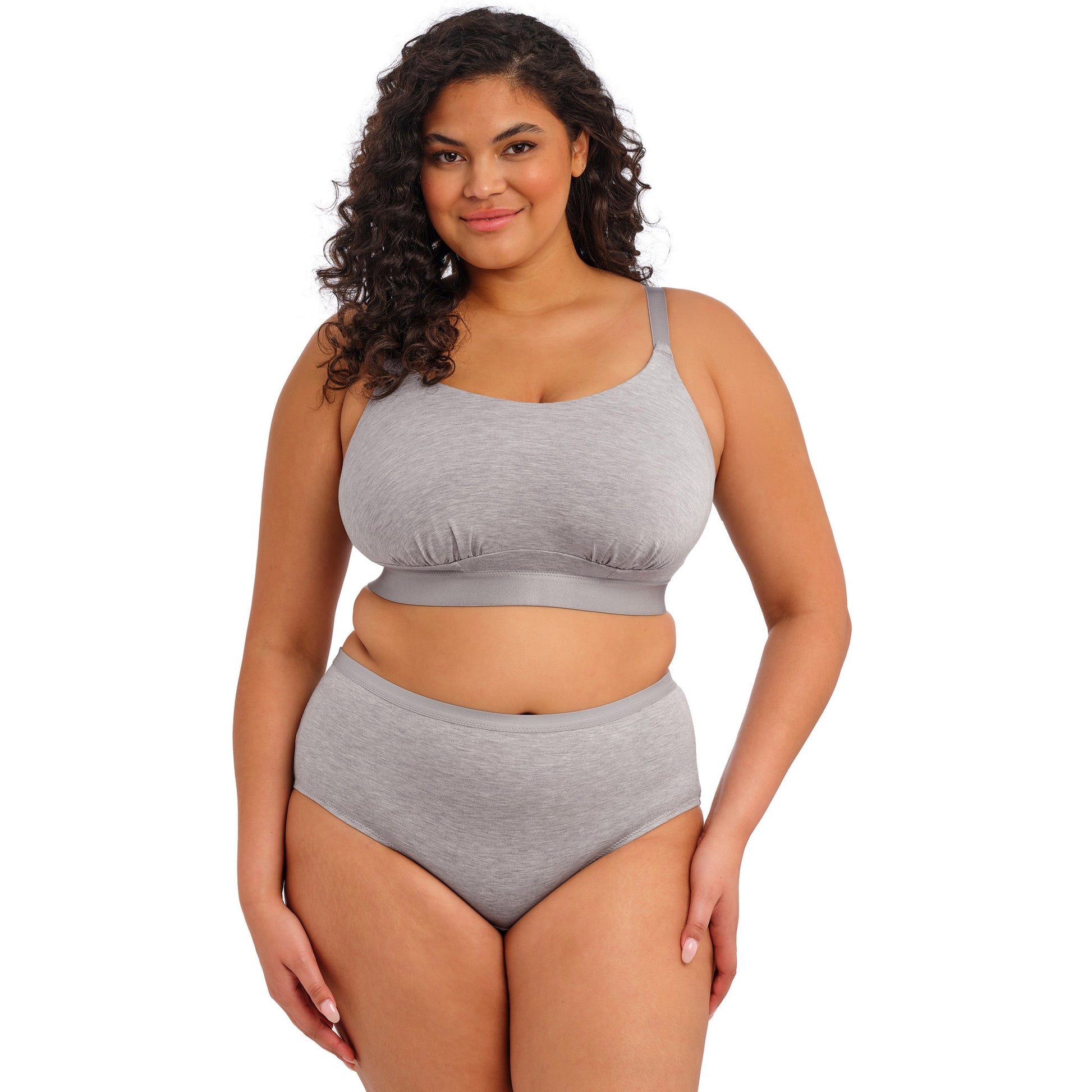 Curvy woman wearing a grey bra and underwear set against a white background
