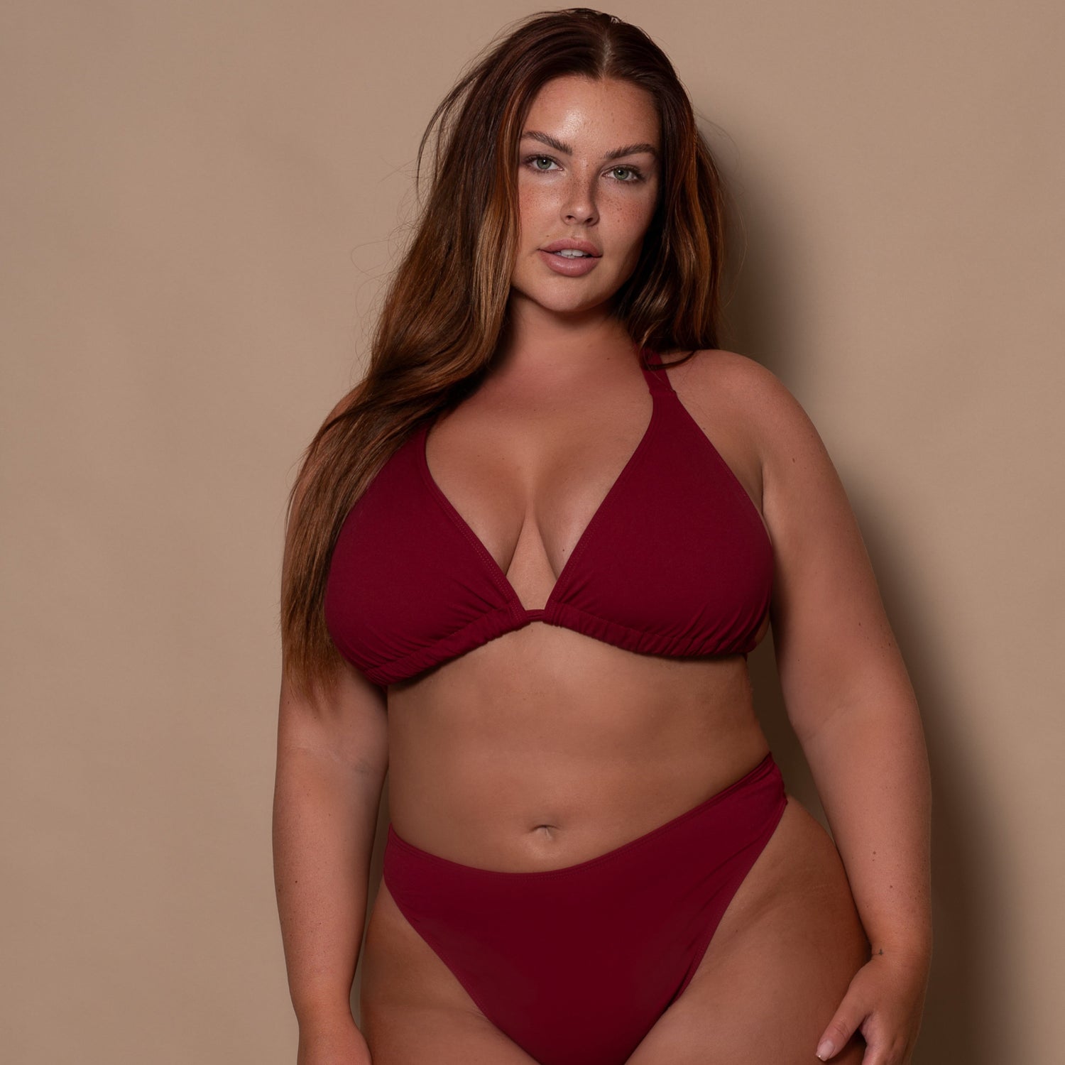 Woman wearing a red bikini against a beige background