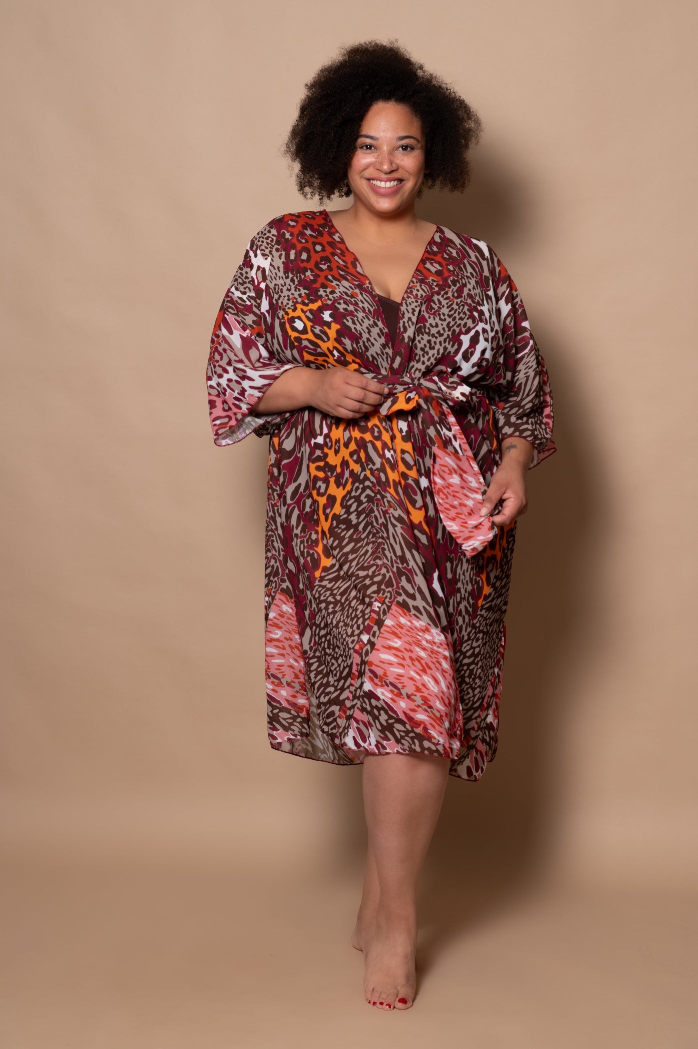 plussize woman wearing a patterned kimono or swimwear cover up against a beige background