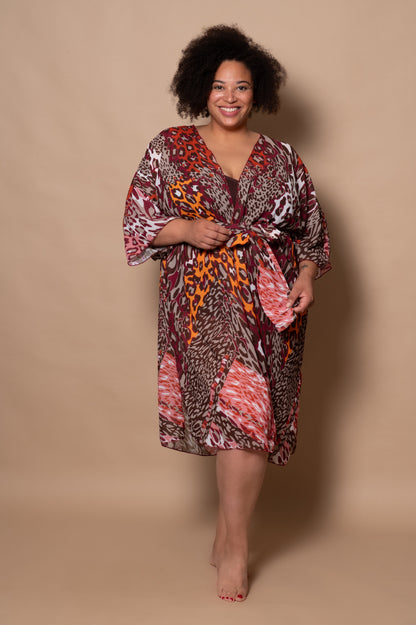 plussize woman wearing a patterned kimono or swimwear cover up against a beige background