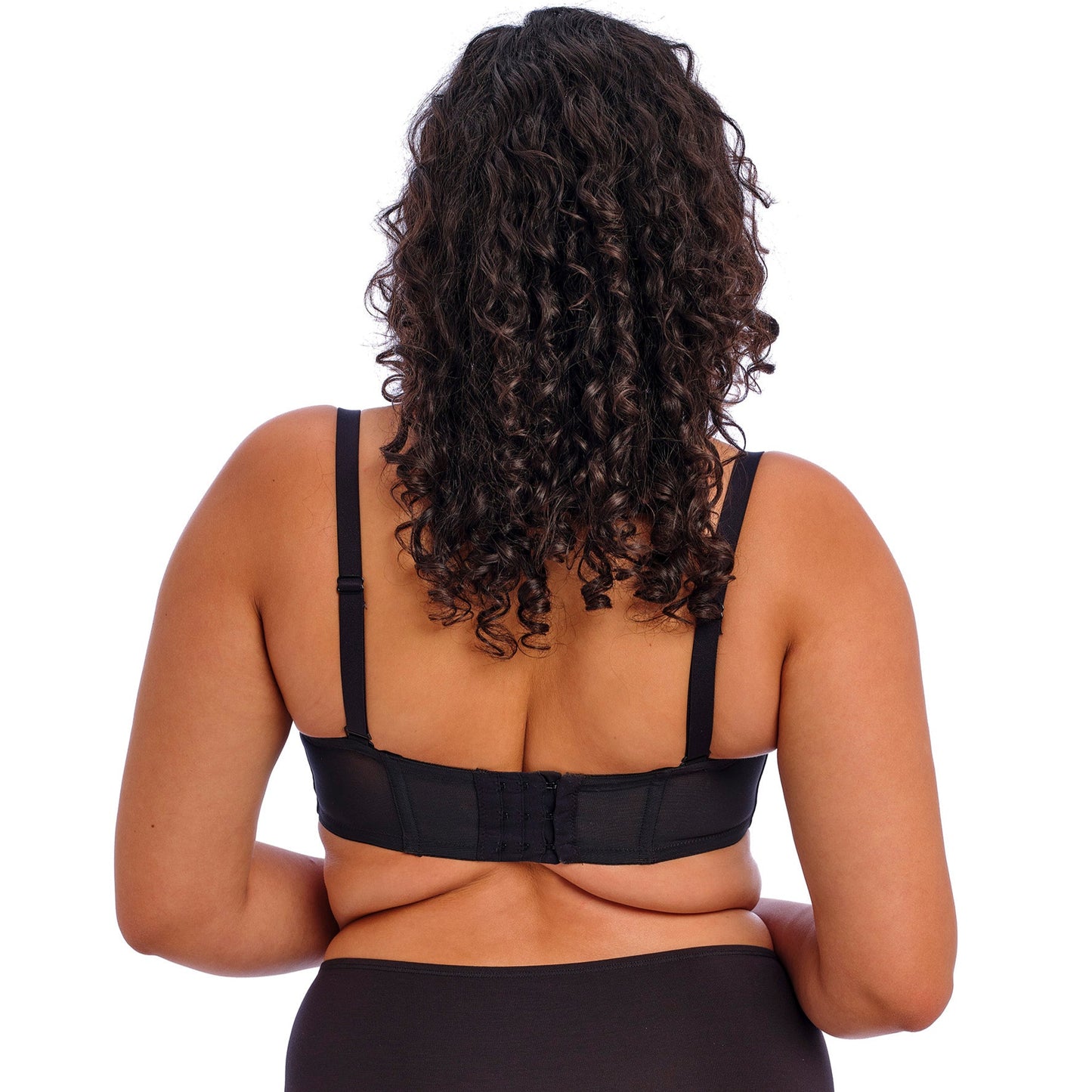 curvy woman wearing a black strapless bra on a white background
