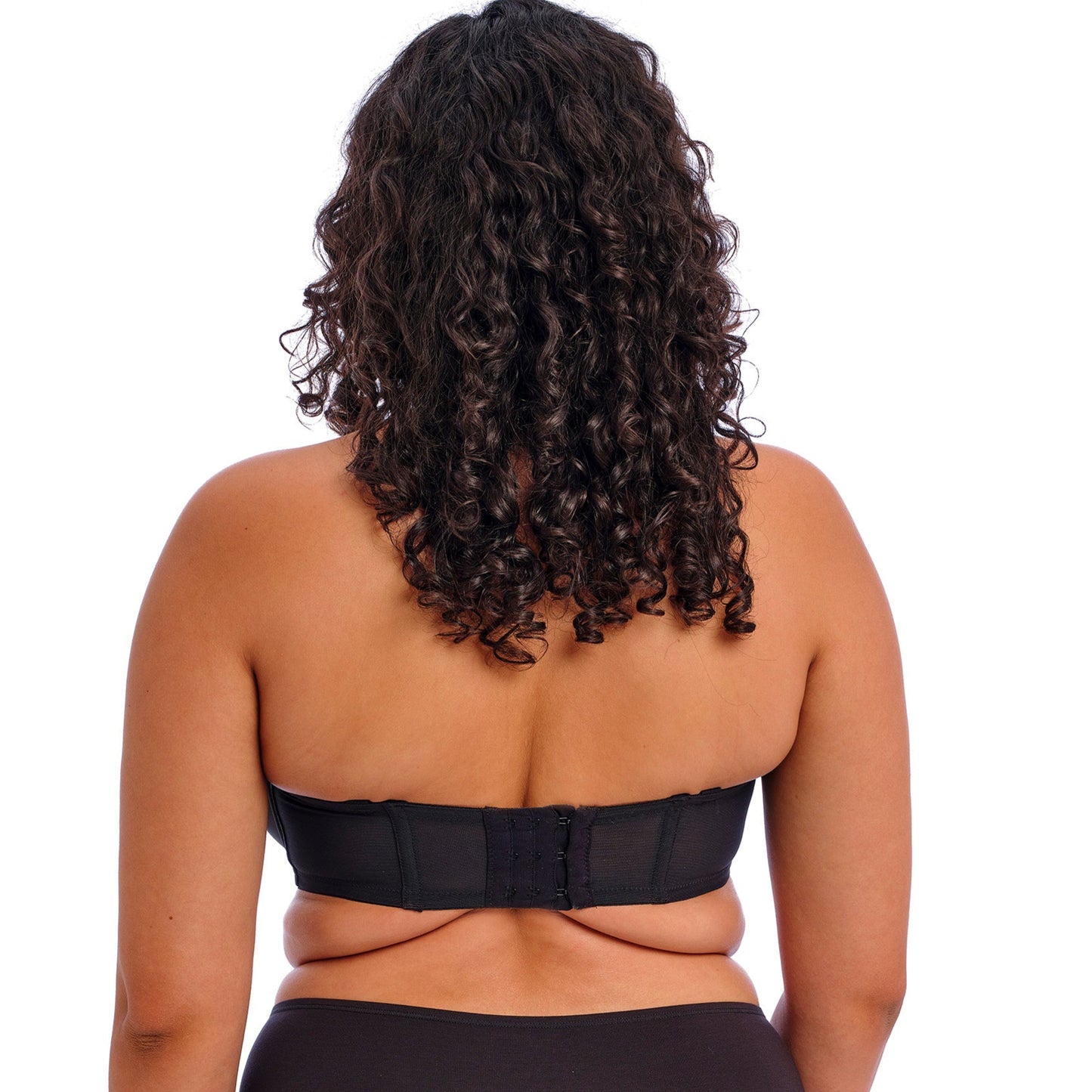 curvy woman wearing a black strapless bra on a white background