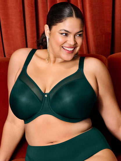 curvy woman wearing an emerald green lingerie set against a red curtain background