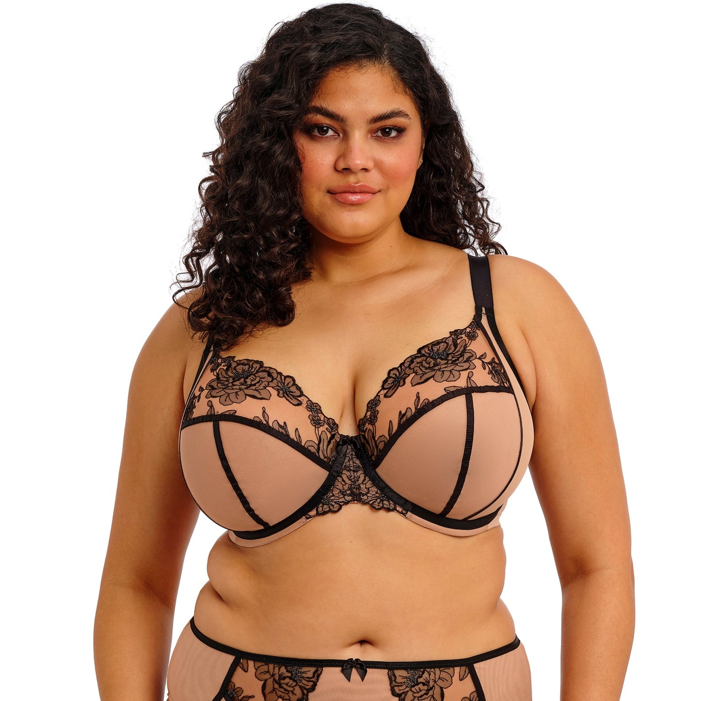 curvyoman wearing a beige lingerie set with black straps and black lace on a white background