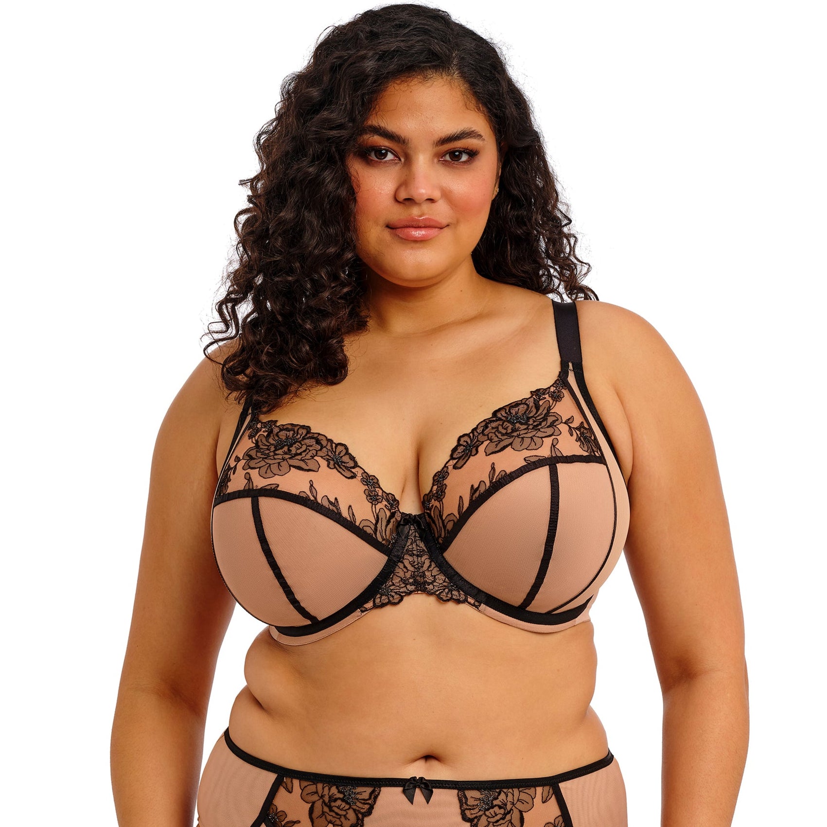 curvyoman wearing a beige lingerie set with black straps and black lace on a white background