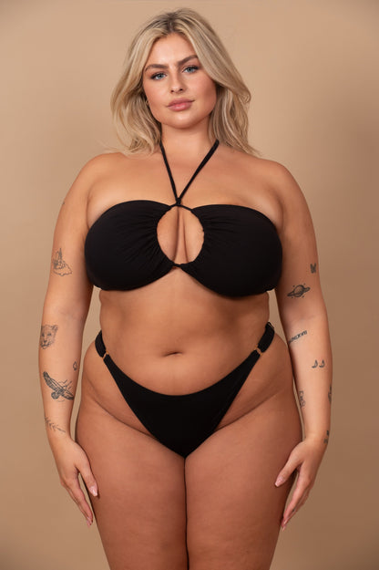curvy woman wearing a black bikini against a beige background