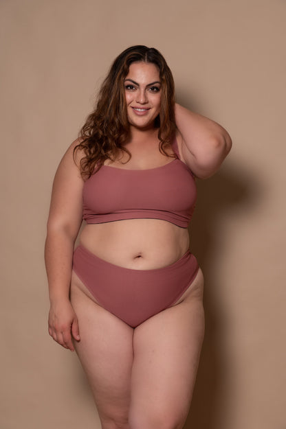 plussize woman wearing a rosewood bikini against a beige background