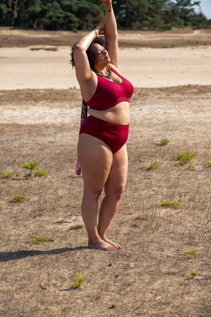 plussize women wearing a red bikini standing on a dry, grassy field.