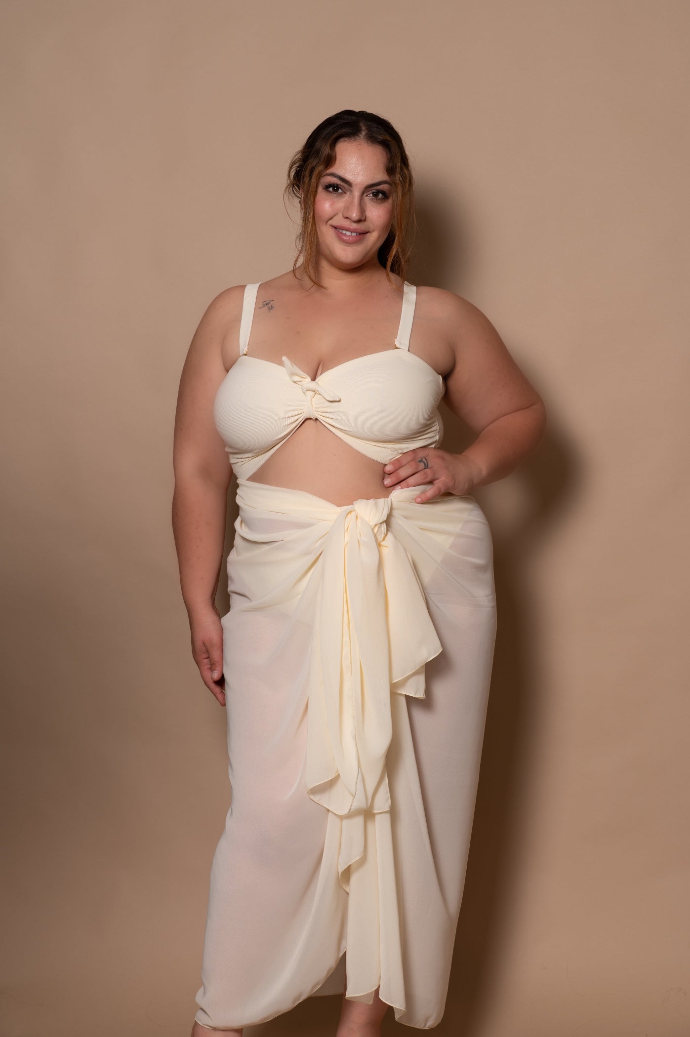 plussize woman wearing a white cream bikini against a beige background