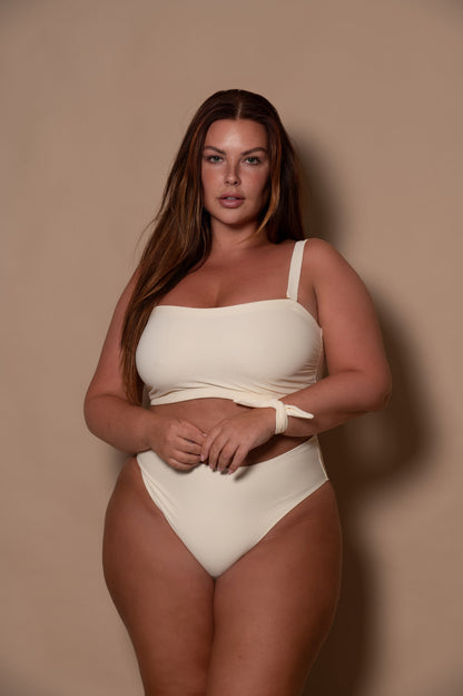 plussize woman wearing a white bikini against a beige background