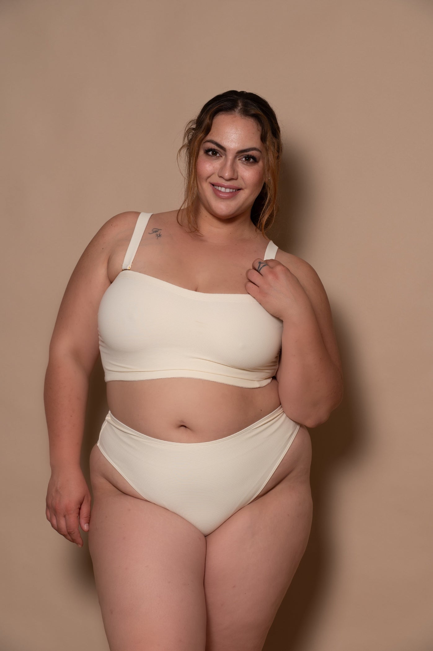 plussize woman wearing a white bikini against a beige background