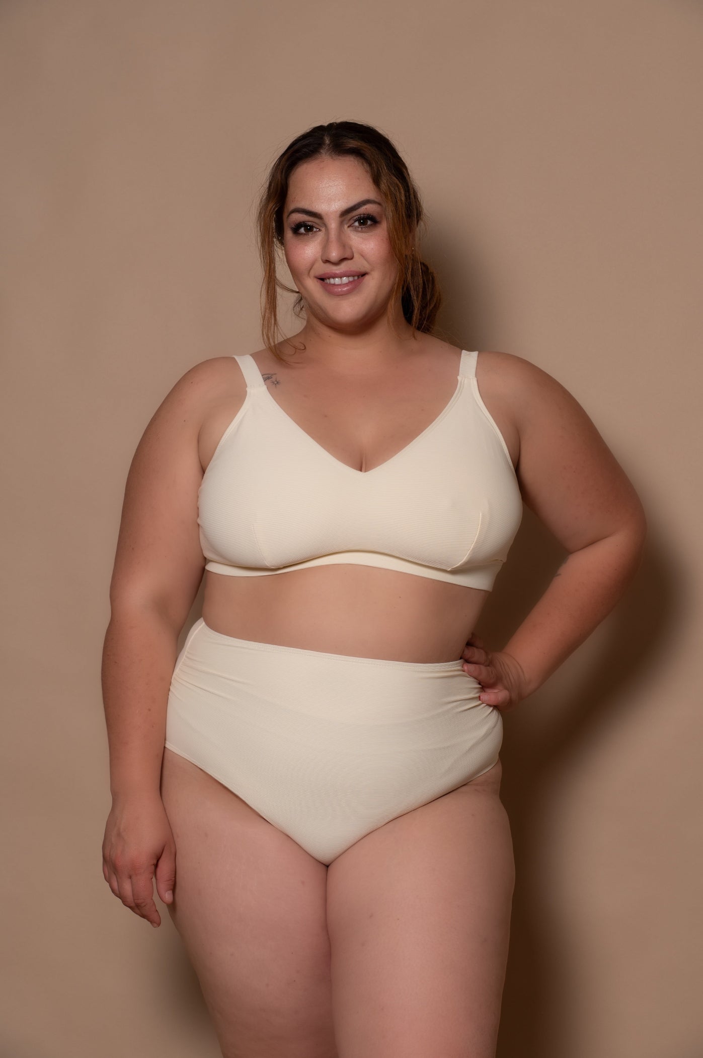 curvy woman wearing a cream - white  bikini against a beige background