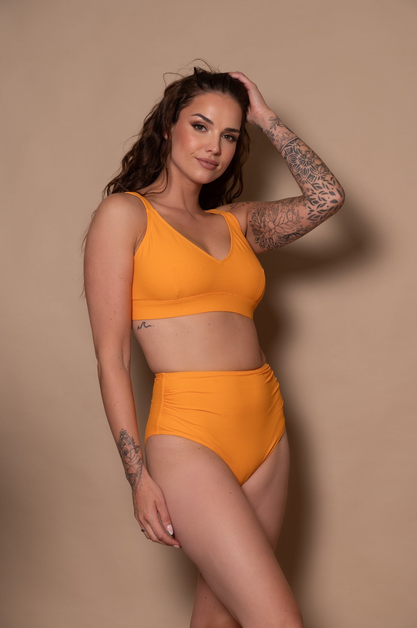 Woman wearing a yellow bikini against a beige background