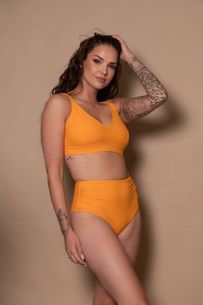 Woman wearing a yellow bikini against a beige background