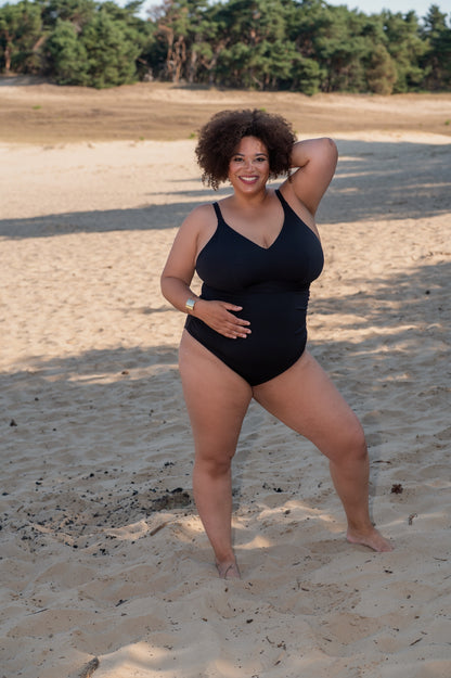 plussize woman wearing a black bikini against a beige background