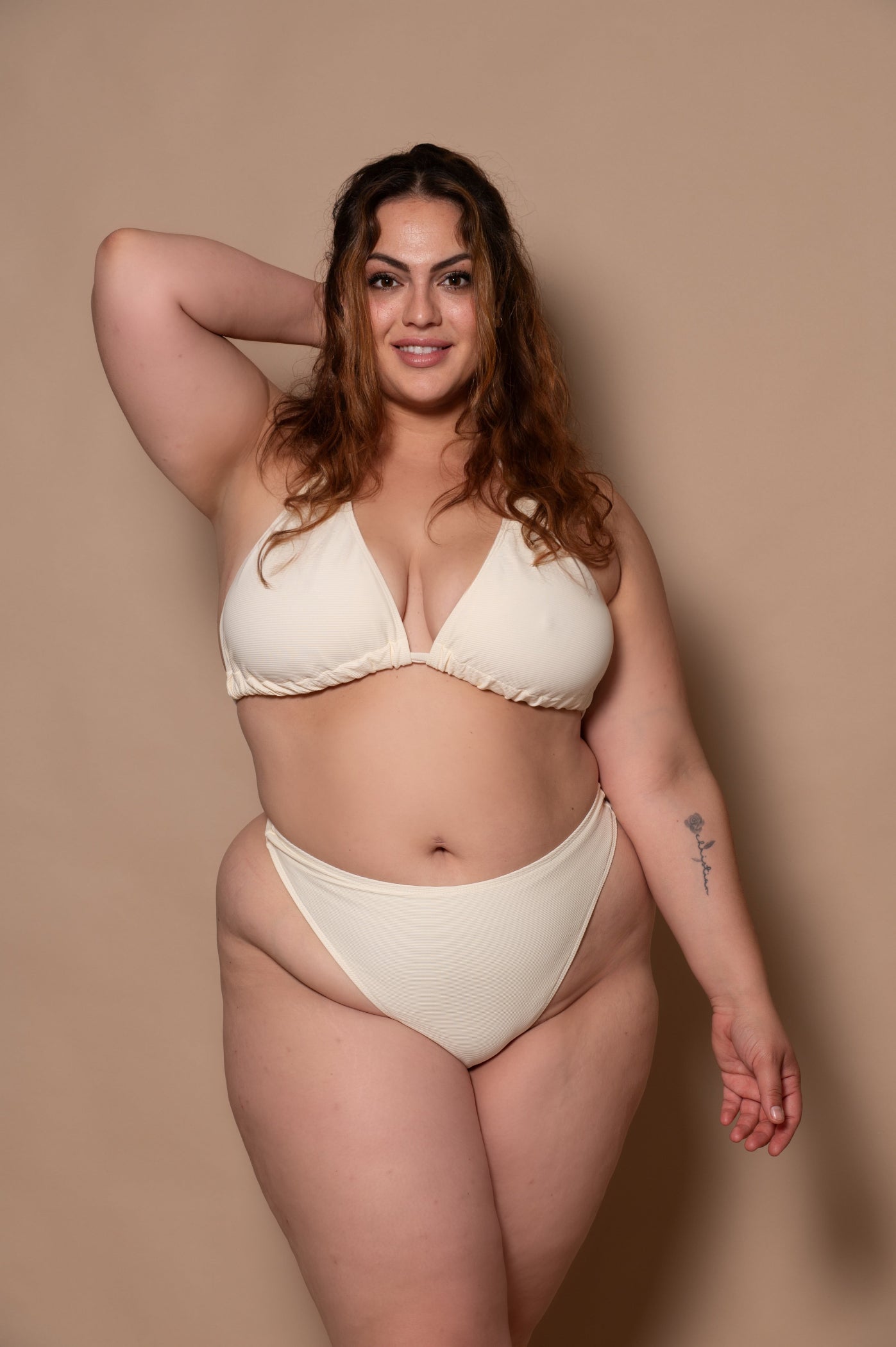 plussize woman wearing a white cream bikini against a beige background