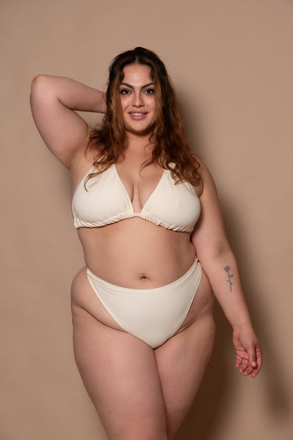 plussize woman wearing a white cream bikini against a beige background