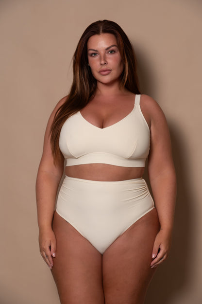 curvy woman wearing a cream - white  bikini against a beige background