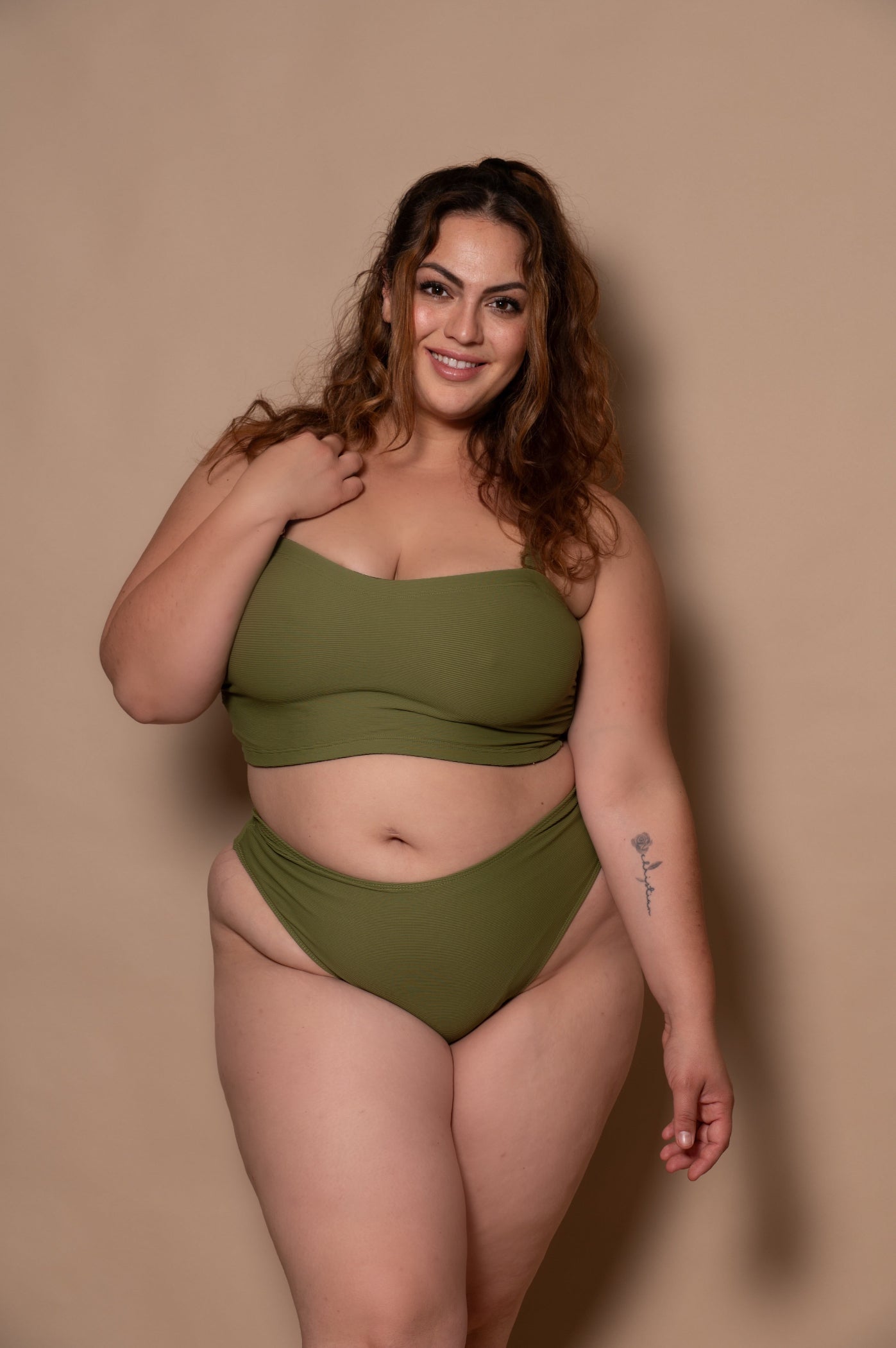 plussize woman wearing a green khaki bikini against a beige background