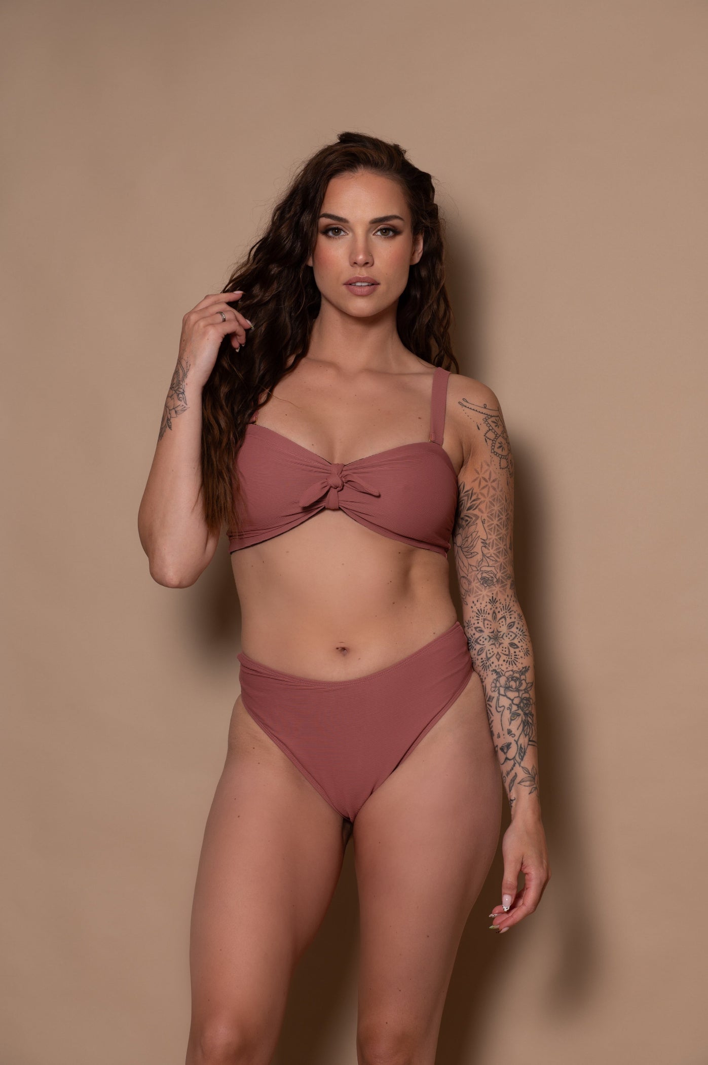 woman wearing a rosewood bikini against a beige background