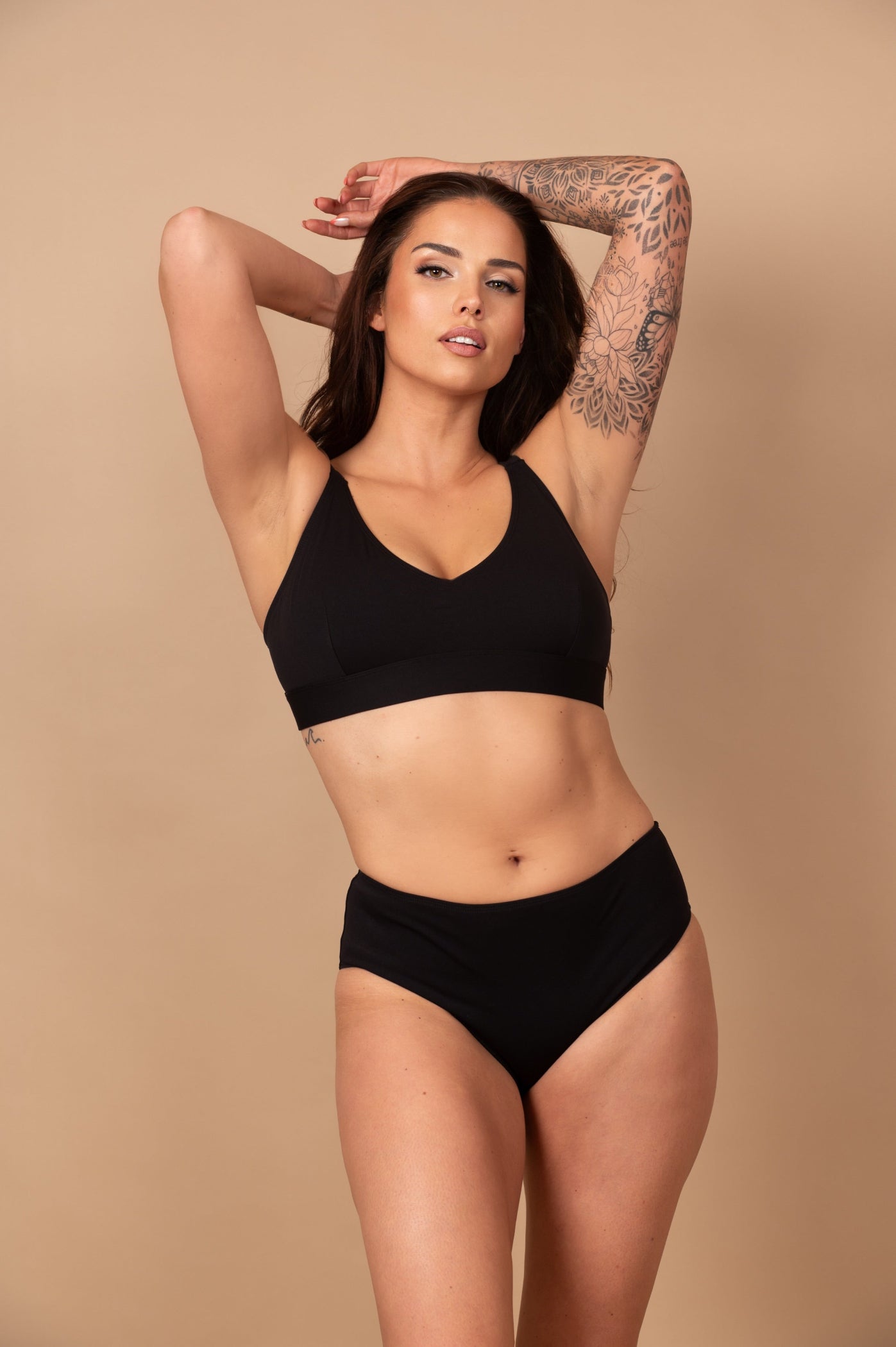 Woman wearing a black bikini against a beige background