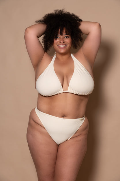 plussize woman wearing a white cream bikini against a beige background