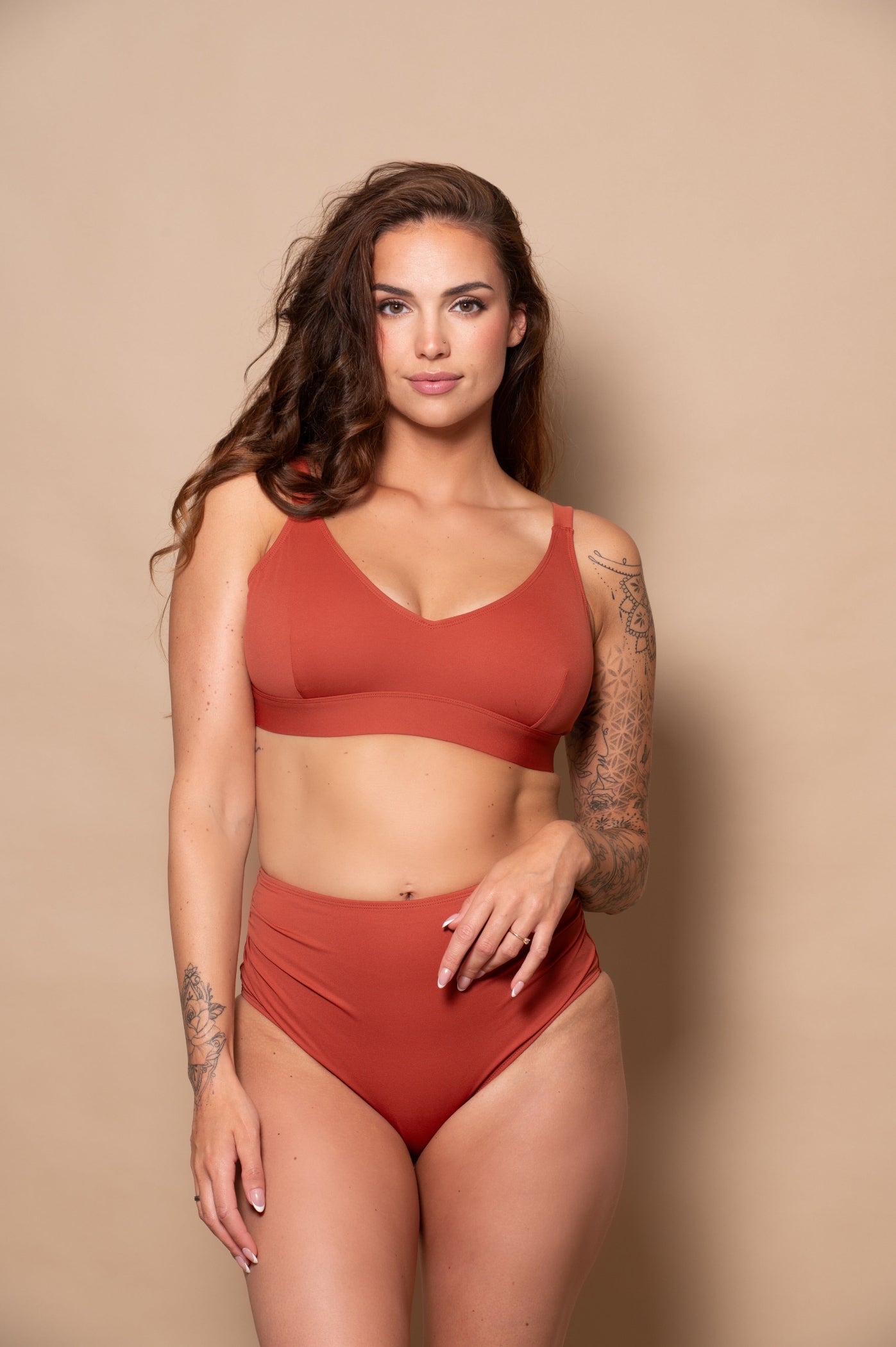 woman wearing a rust red bikini  against a beige background