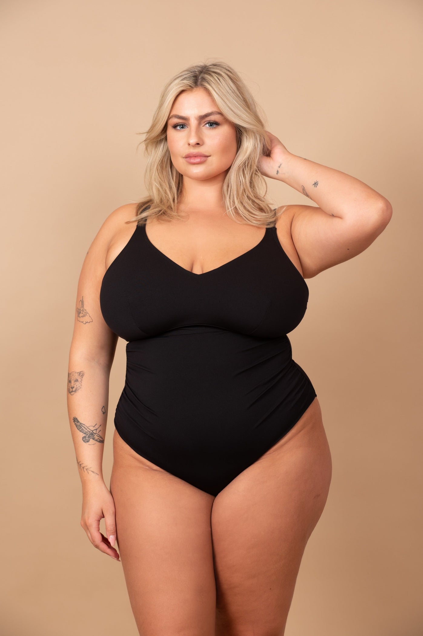curvy woman wearing a black bikini against a beige background