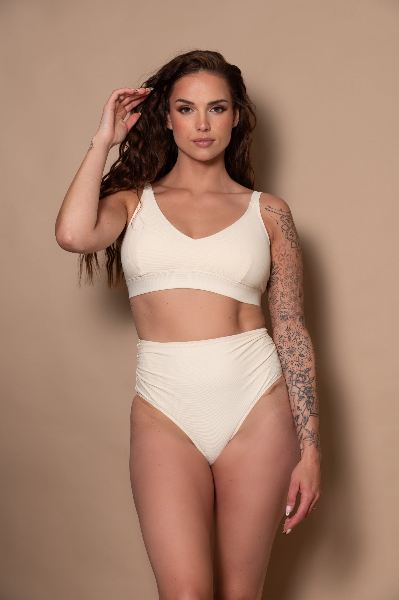 woman wearing a cream - white  bikini against a beige background
