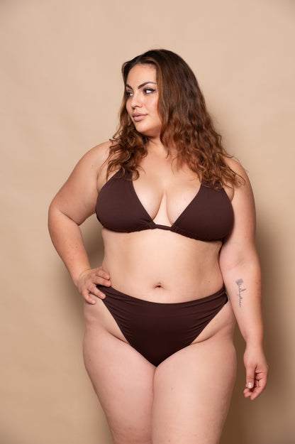 plussize woman wearing a chocolate brown bikini set against a beige background