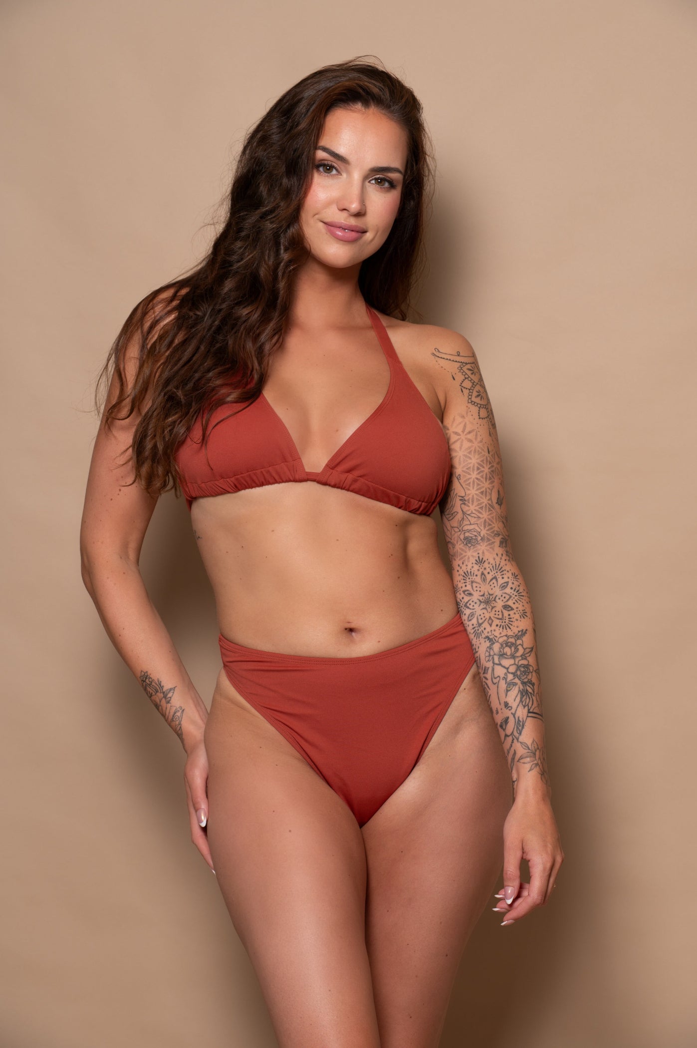 woman wearing a rust red bikini set against a beige background