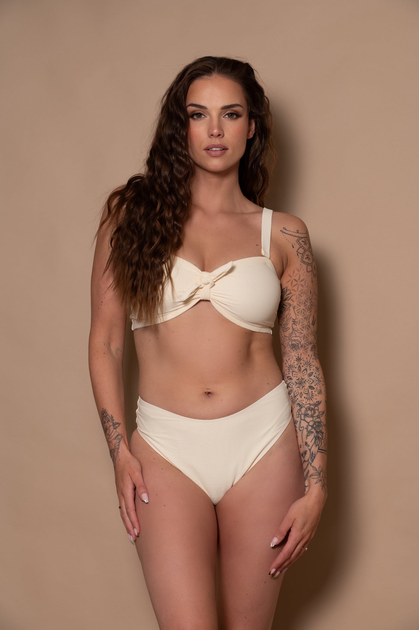 woman wearing a white cream bikini against a beige background